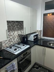 cocina con fogones horno superior junto a un microondas en Lovely 2 Bedroom Apartment with free parking en Mánchester