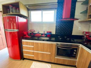 eine Küche mit einem roten Kühlschrank und einer Spüle in der Unterkunft Apartamento Completo no Beach Place Cumbuco - Apto Luxo in Cumbuco