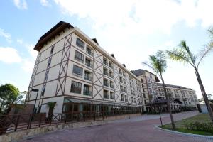 een groot wit gebouw met een palmboom ervoor bij Vista Azul Apart Hotel - Vista Pinheiros in Aracê