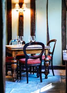 una mesa de madera con sillas y copas de vino. en The Peacock Inn en Chelsworth