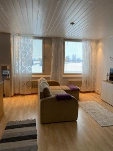 a living room with a couch and two windows at Apartment Isokatu in Kokkola
