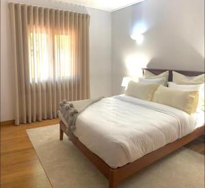 a bedroom with a bed with white sheets and a window at TOP BEACH HOUSE in Costa da Caparica