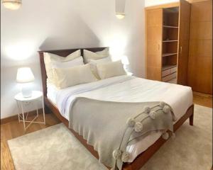 una camera da letto con un grande letto con lenzuola e cuscini bianchi di TOP BEACH HOUSE a Costa da Caparica