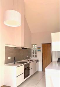 - une cuisine avec des placards blancs, un évier et une lampe dans l'établissement TOP BEACH HOUSE, à Costa da Caparica