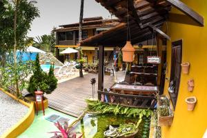 a wooden deck next to a house with a koi pond at Pousada A Flor da Terra in Arraial d'Ajuda