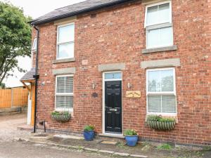 a brick house with a black door and two potted plants at Corner House Cottage in Ilkeston