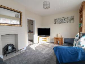 a living room with a fireplace and a tv at Corner House Cottage in Ilkeston