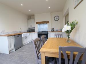 una cucina con tavolo in legno e vaso di fiori di Corner House Cottage a Ilkeston