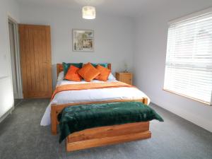 una camera da letto con un letto con cuscini arancioni e verdi di Corner House Cottage a Ilkeston