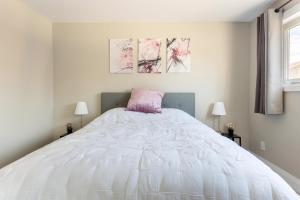 a bedroom with a large white bed with three paintings on the wall at ENTIRE 2 BEDROOM APARTMENT DOWNTOWN - u2 in Kitchener