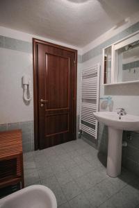a bathroom with a sink and a wooden door at Residence Aquila - Bilo Testa di Comagna in Brusson