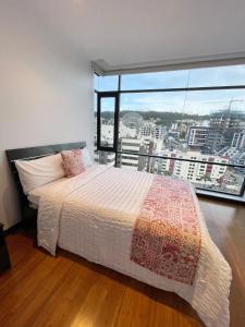 a bedroom with a bed and a large window at Departamento de Lujo La Carolina - Quicentro Shopping in Quito