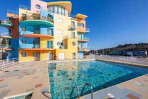 een gebouw met een zwembad voor een gebouw bij Casa das Cores in Albufeira