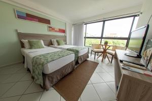 a hotel room with two beds and a desk with a computer at Nobile Inn Cabo Branco in João Pessoa +14 photos