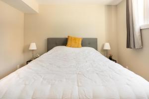 a white bed in a bedroom with two lamps at ENTIRE 2 BEDROOM APARTMENT DOWNTOWN - u1 in Kitchener