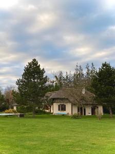 Casa blanca con césped y árboles en Maison traditionnelle Normande avec piscine, en Hotot-en-Auge