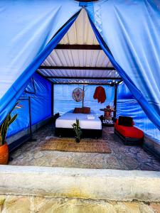 洛斯桑托斯Parador La Mesa Redonda Hotel y Glamping的一间蓝色帐篷内的卧室