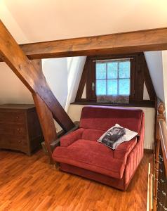 un sofá rojo en una habitación con ventana en Maison traditionnelle Normande avec piscine, en Hotot-en-Auge