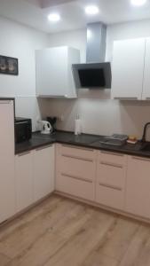 a kitchen with white cabinets and black counter tops at Apartament Morski przy plazy in Darłówko