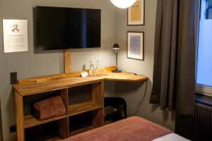 a room with a desk with a television on the wall at Storyhotel Bergischer Hof Königswinter in Königswinter
