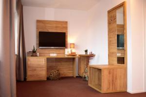a living room with a tv and a wooden entertainment center at Landhaus Sonne in Hergensweiler