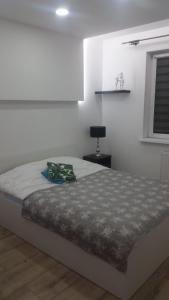 a white bedroom with a bed and a window at Apartament Morski przy plazy in Darłówko