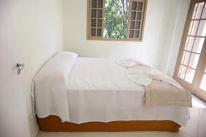 białe łóżko w pokoju z 2 oknami w obiekcie Residencial Mb w mieście Conservatória
