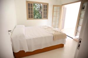 uma cama branca num quarto com uma janela em Residencial Mb em Conservatória