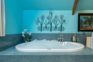 a bath tub with flowers on a blue wall at The Meeting House - Atmospheric 16th Century Merchants House in Ashburton