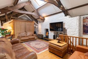 a living room with leather furniture and a stone wall at The Meeting House - Atmospheric 16th Century Merchants House in Ashburton