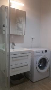 a white bathroom with a washing machine and a sink at Apartament Morski przy plazy in Darlowko +5 photos