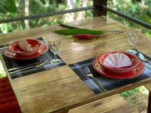 una mesa de madera con 2 platos rojos y copas de vino en Pequeño Paraiso 1, en Punta Uva