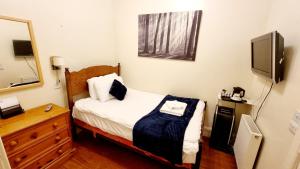 una piccola camera con letto e televisore di The Guards Hotel a Edimburgo
