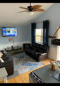 ein Wohnzimmer mit einem Sofa und einem Deckenventilator in der Unterkunft Seaside chalet,Aboiteau beach cottage rentals,cap pele in Cap-Pele