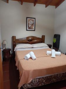 1 dormitorio con 1 cama con toallas en Cabañas Ecos del Valle en Los Reartes
