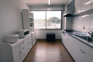 舞鶴的住宿－Manabiamu 4F - Vacation STAY 58913v，一间厨房,配有白色的橱柜和大窗户