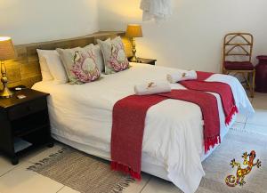 a bedroom with a large white bed with a red blanket at Sabie River Bush Lodge in Hazyview