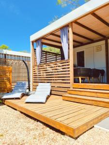 una terrazza in legno con 2 sedie a sdraio di Bungalow Home Sweet Home - Logement complet a Biograd na Moru