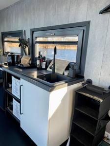 una cucina con lavandino e bancone con finestra di Unique Water Stay Tiny Hausboot für 2 Personen a Zehdenick