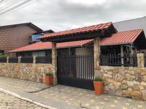 una casa con una valla negra y un muro de piedra en Suites da Lu, en Penha