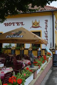 a restaurant with tables and an umbrella and flowers at Hotel Koruna in Karlštejn