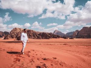 een man in de woestijn met bergen op de achtergrond bij Wadi Rum Nights in Wadi Rum