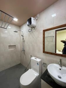 een badkamer met een toilet, een wastafel en een spiegel bij Courtyard Guesthouse in Huraa