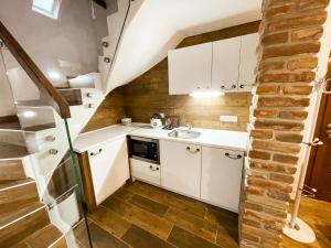 a small kitchen with white cabinets and a brick wall at Apartmánový dům 13 Mezonet 1 in Seč