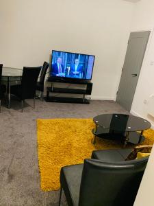 sala de estar con TV y alfombra amarilla en City Blessed Aptm 3 with Free Parking, en North Shields