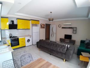 een woonkamer met een bank en een keuken met gele kasten bij Canans Home in Demre