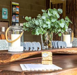 una mesa con un jarrón de flores y un centro de mesa en Klein Plekkie Self Catering Accommodation, en Addo