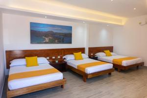 a hotel room with two beds with yellow pillows at Hotel Las Ninfas in Puerto Ayora