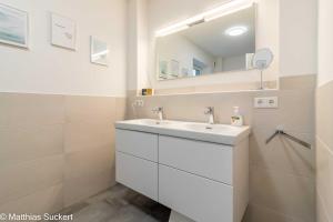 a bathroom with a white sink and a mirror at Fewo Fiete Whg 4 Haus Kachelotplate in Hooksiel