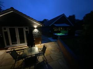 un patio con mesa y sillas por la noche en Luxury 5* Woodland Retreat, In The Woods. en Skegness